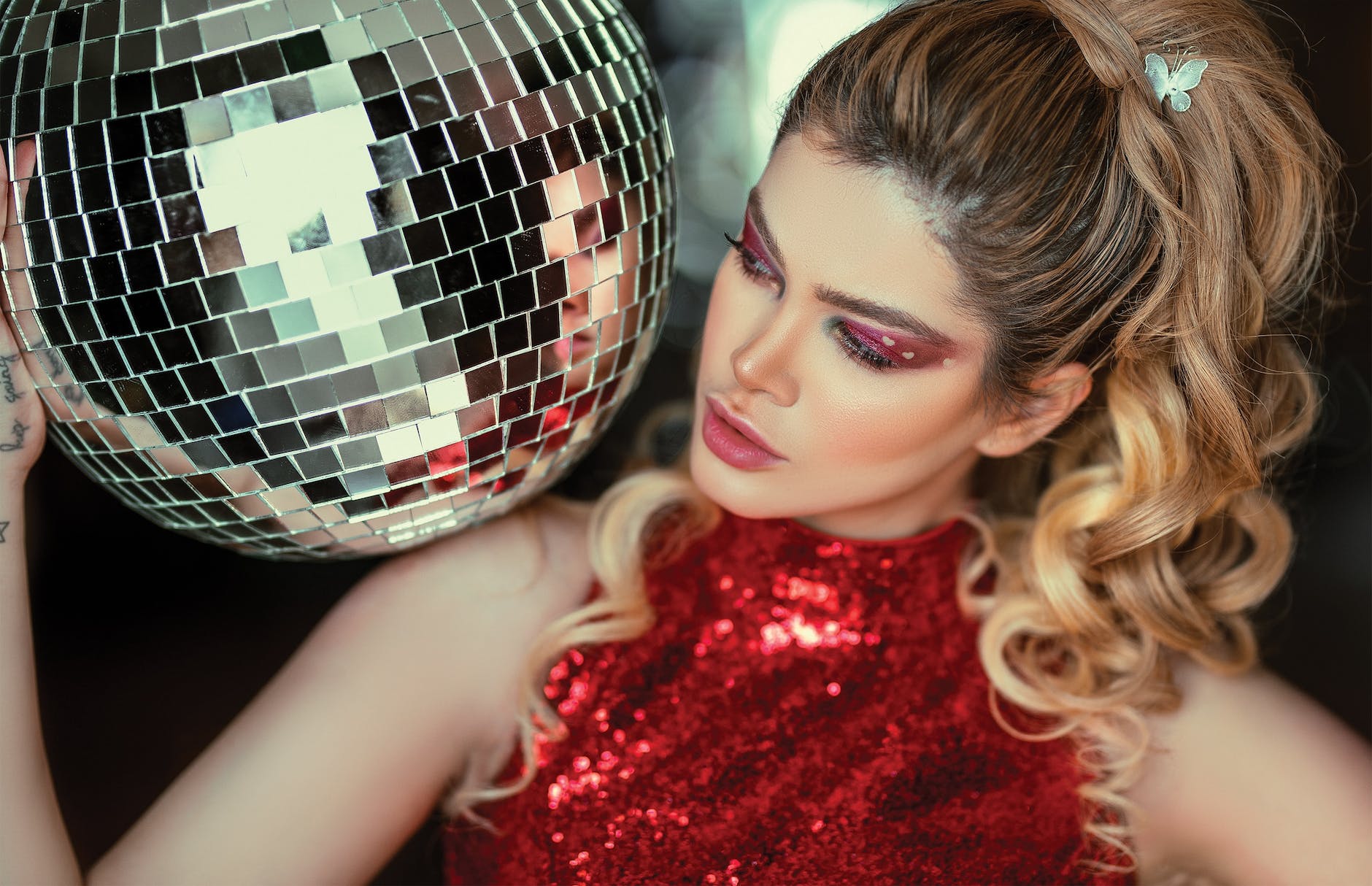 photo of a woman in red glitter halter top holding disco ball